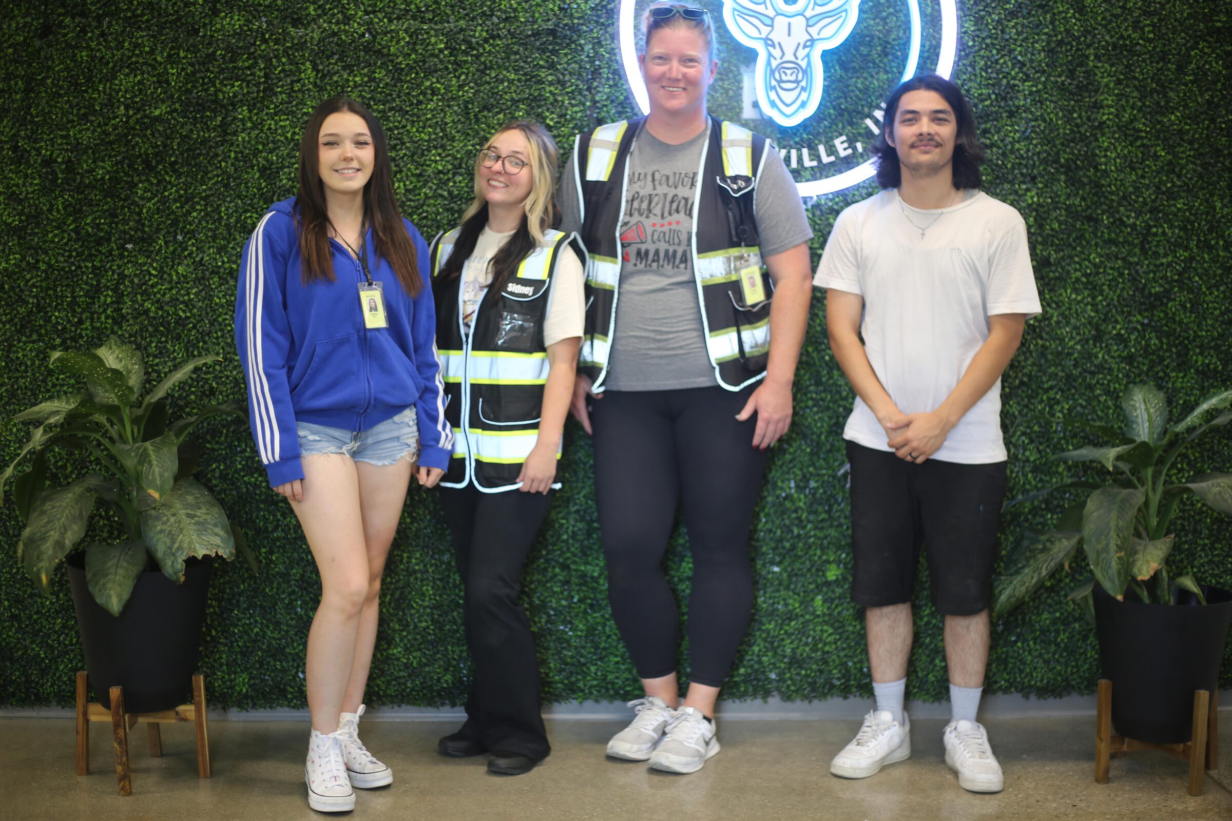 Four TALA Logistics team members standing together in front of the illuminated sign at the delivery station.